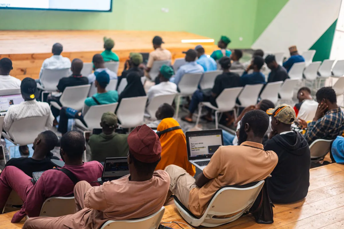 A full room of attendees seated and facing a stage during a Benin City builder meetup.