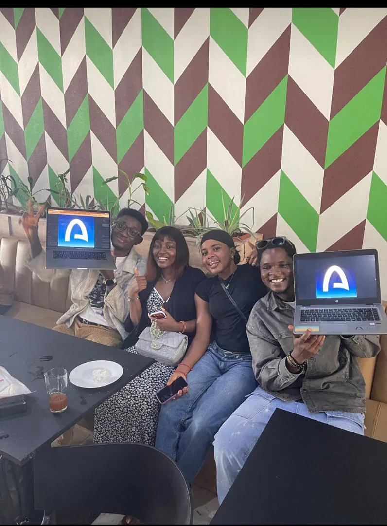 Four attendees holding up laptops displaying the Arc logo at a Benin City meetup.