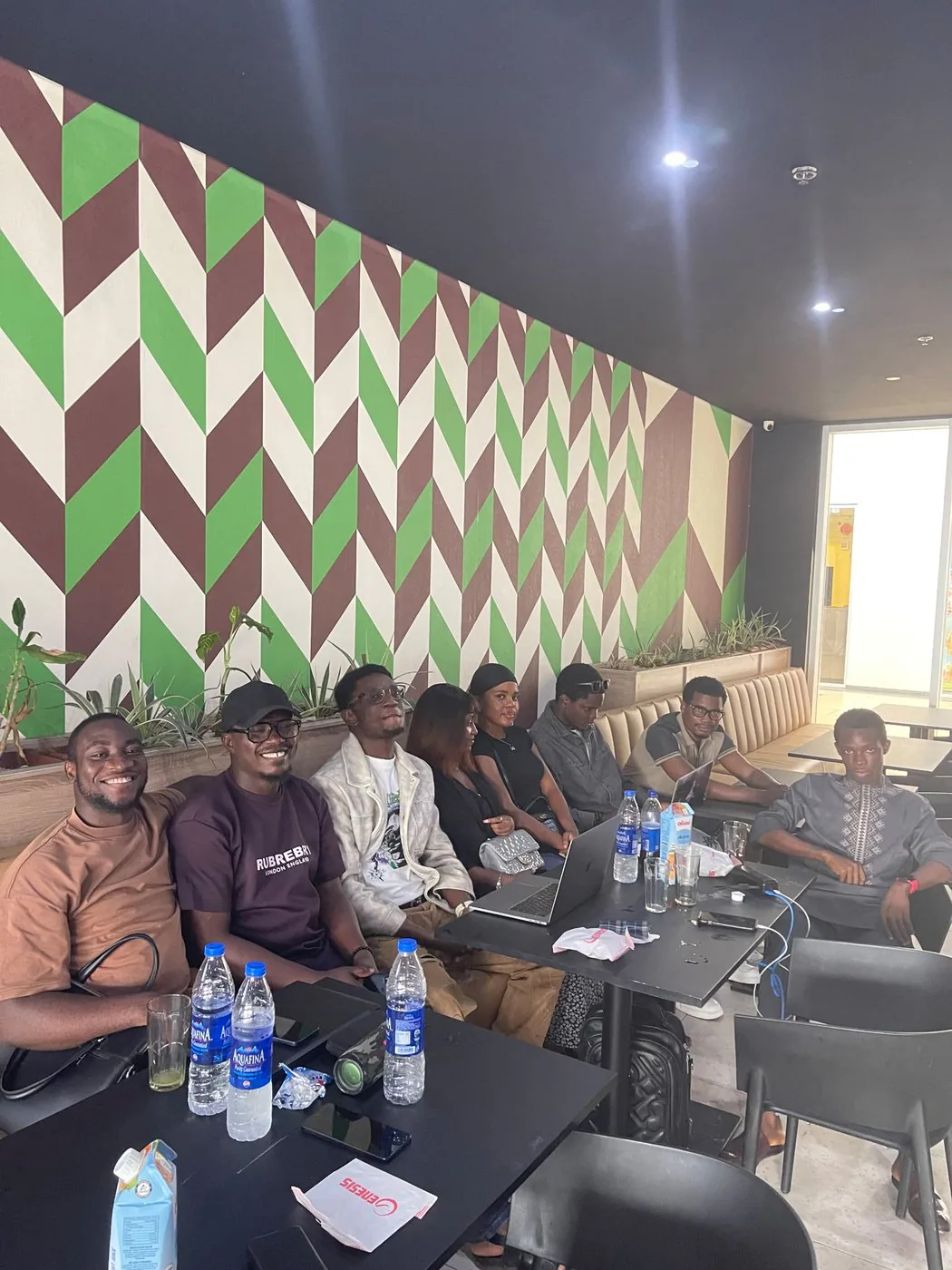 A row of builders seated at a cafe table during an informal Benin City working session.